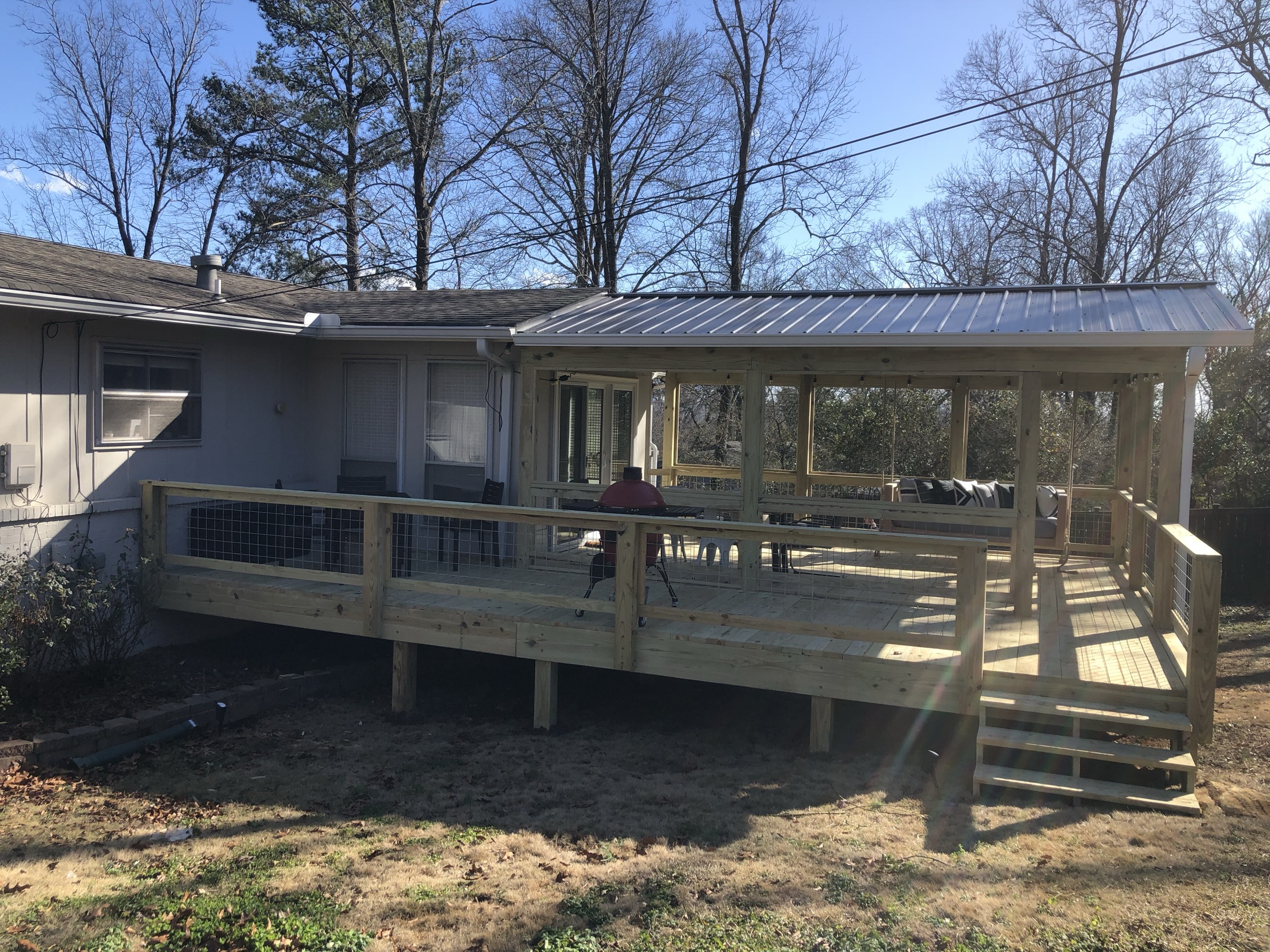 Furnished screened porch with metal roof built by Redbone Woodworks